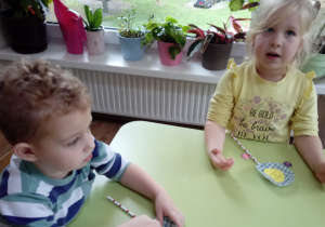 Dzieci wykonują kwiatka z papierowych elementów